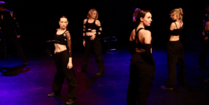 Billede af fire dansere på en mørk, let oplyst scene